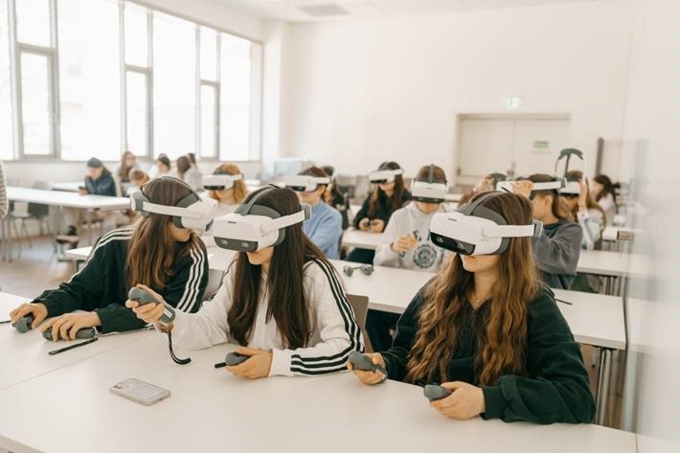 Mehrere Girls' Day-Teilnehmerinnen in einem Raum tragen VR-Headsets und halten Controller, um virtuelle Realität zu erleben