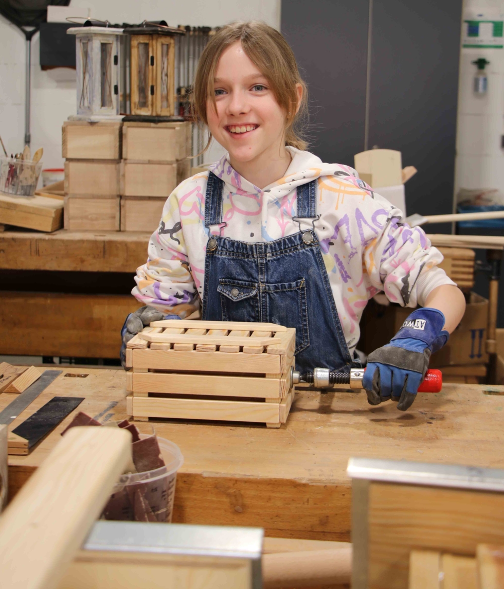 Mädchen mit Holzkasten und Schraubzwinge