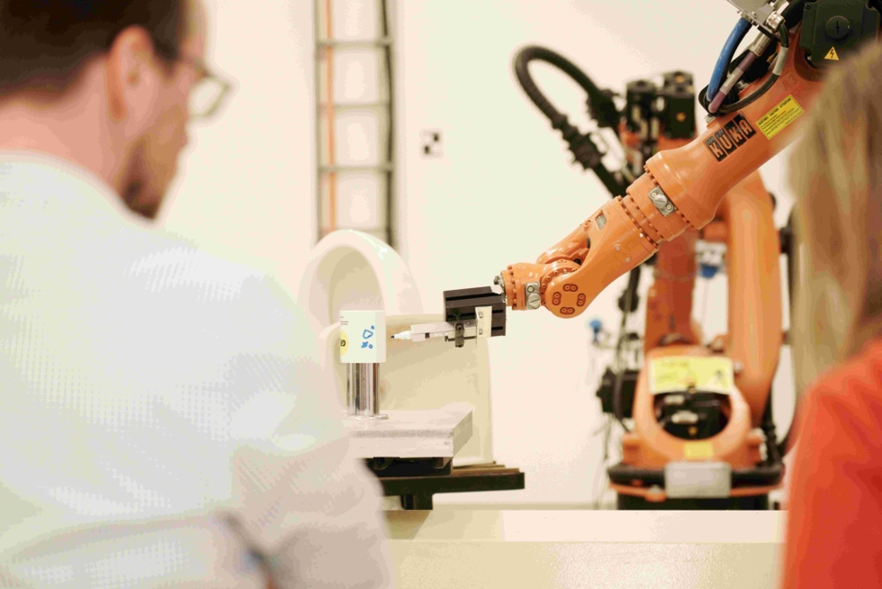 Girls'Day-Teilnehmerinnen und Mitarbeiter vor Computerarm