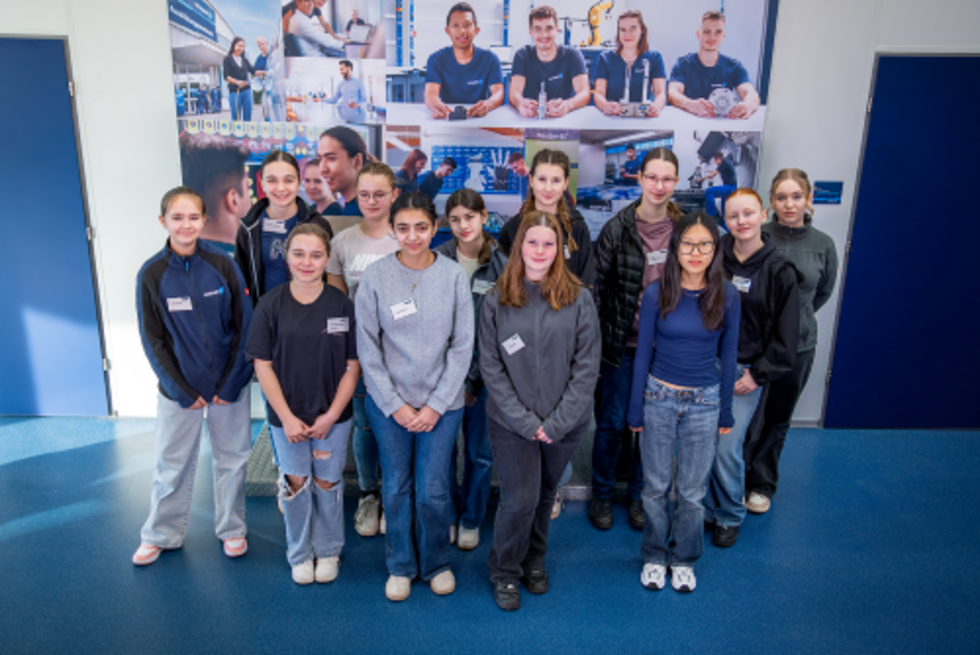 Girls' Day-Teilnehmerinnen, stehend vor einem Informationsbanner mit verschiedenen Berufsfeldern