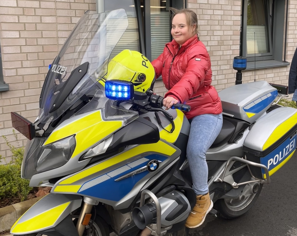 Mädchen sitzt auf einem Polizeimotorrad.