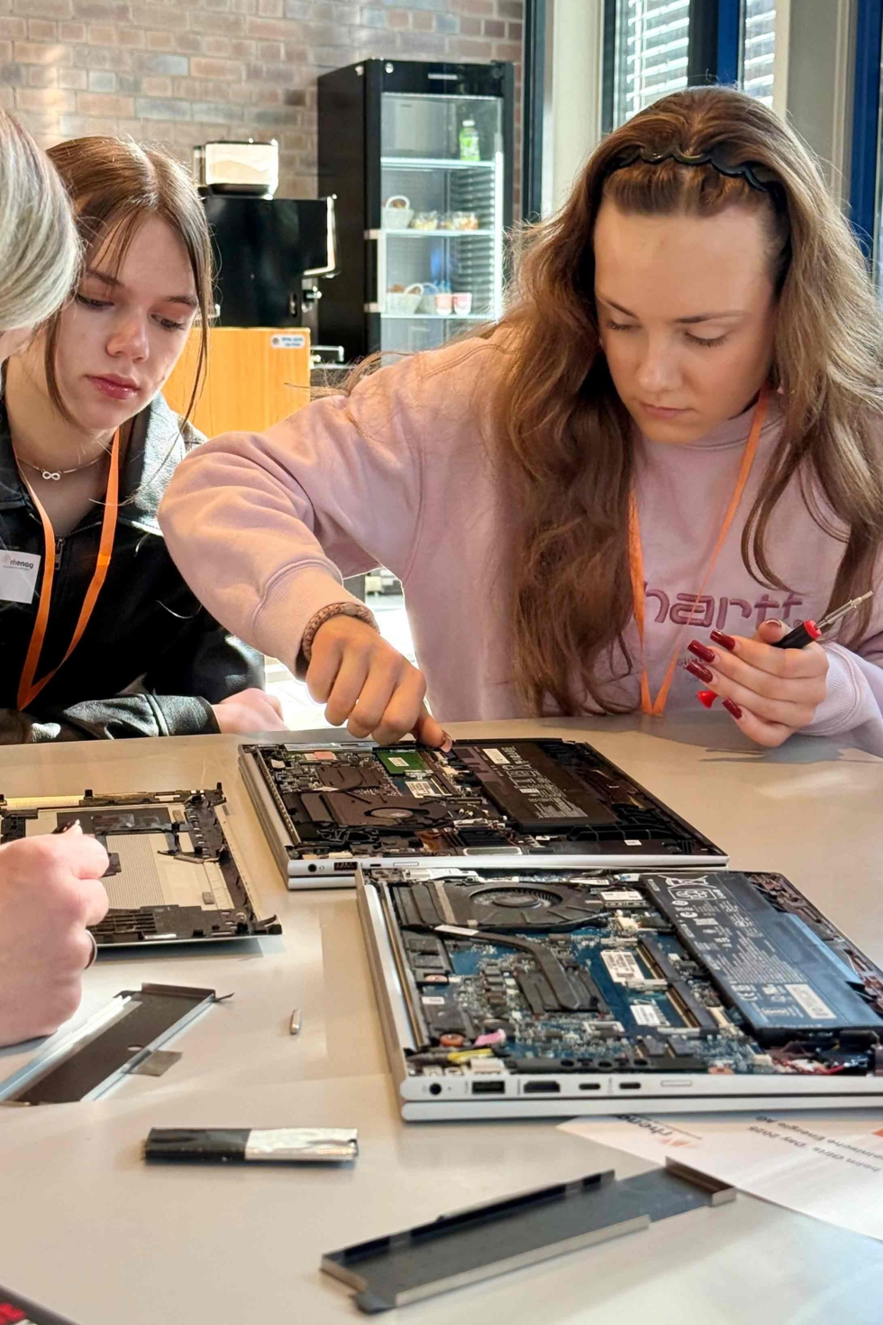 Teilnehmerinnen des Girls'Day schrauben an Computerteilen, eine konzentriert mit Schraubenzieher, die andere beobachtet