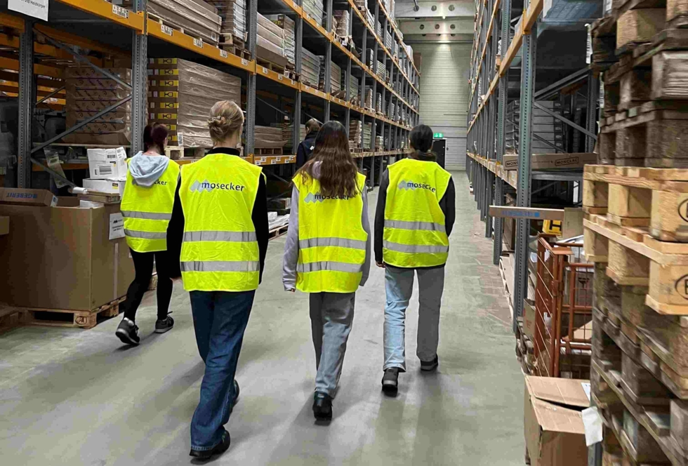 Girls'Day-Teilnehmerinnen in Warnwesten in Lagerhalle