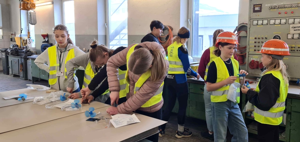 Girls' Day-Teilnehmerinnen arbeiten in Sicherheitswesten und Helmen an technischen Projekten