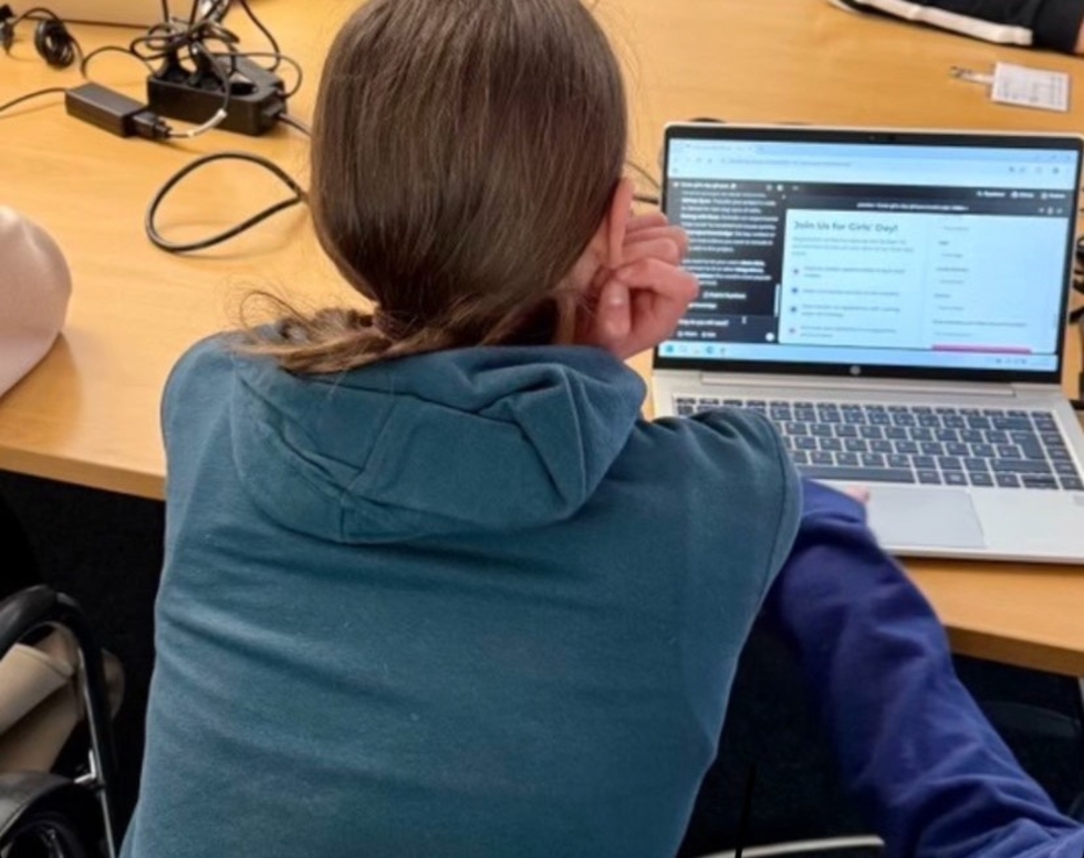Girls'Day-Teilnehmerinnen mit Warnwesten von hinten fotografiert vor einem Computer