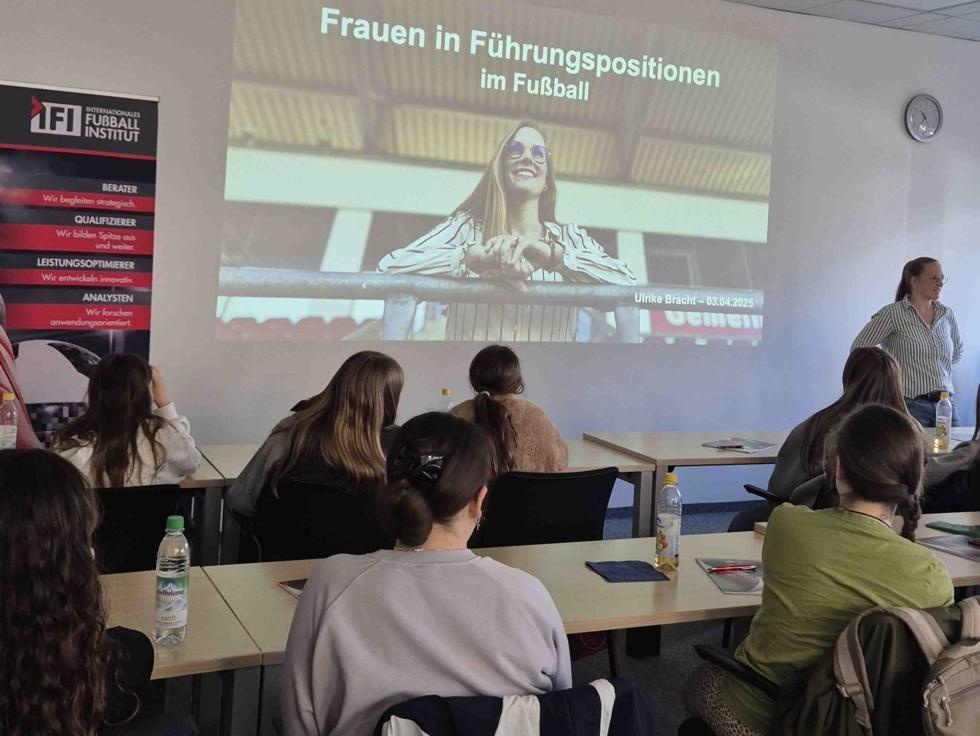 Mädchen von hinten fotografiert sitzen vor einer Präsentation