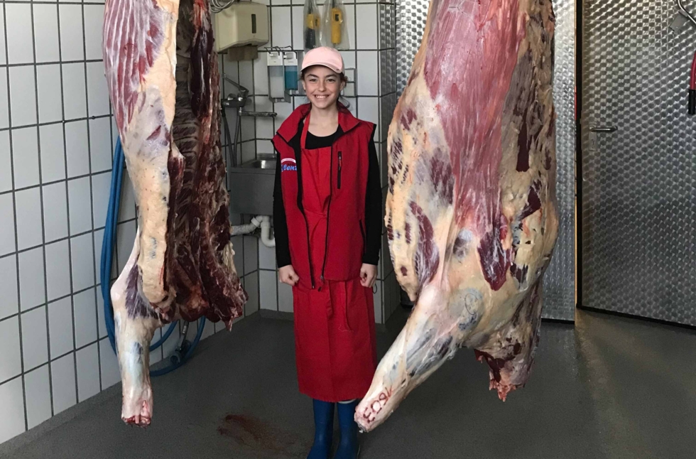 Mädchen zwischen Kuhhälften in Metzgerei