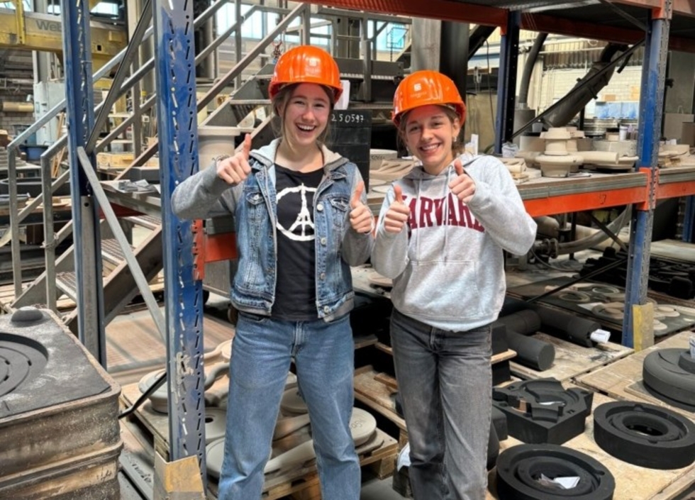 Girls'Day-Teilnehmerinnen mit Helm vor einem Hochregal