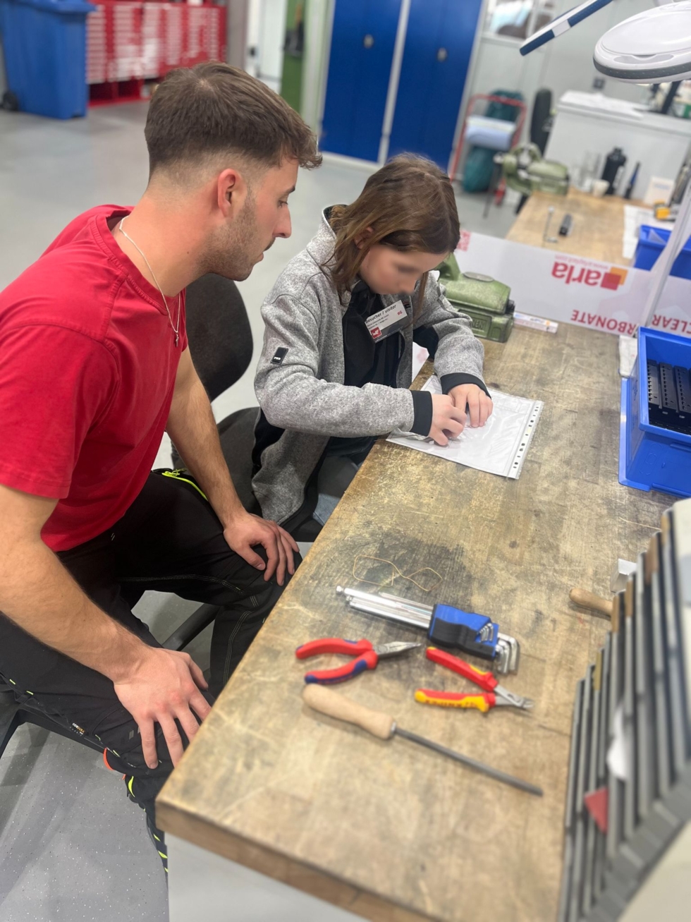 Girls'Day-Teilnehmerin mit Mitarbeiter an Werkbank