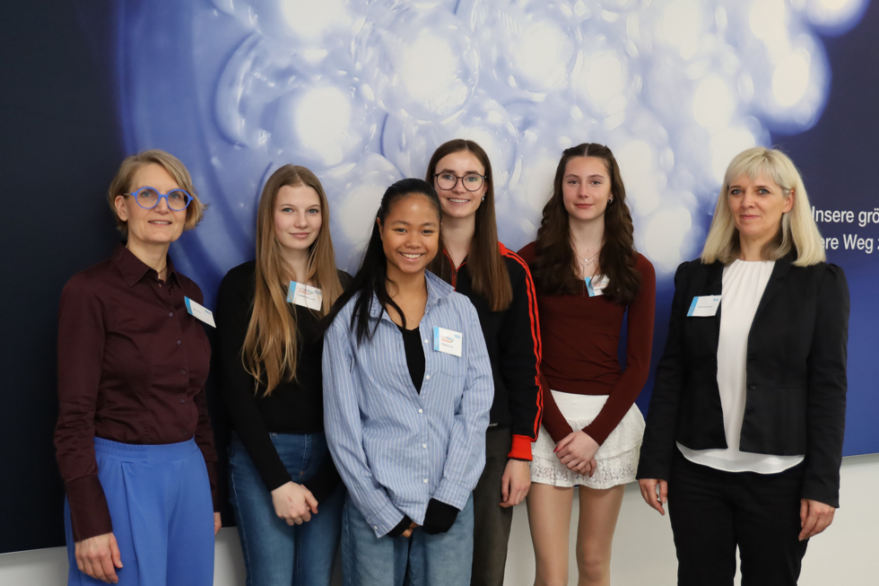 Girls'Day-Teilnehmerinnen mit Mitarbeiterinnen vor Firmenlogo