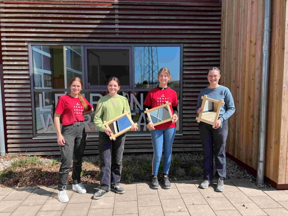 Girls'Day-Teilnehmerinnen mit Mitarbeiterin vor Firmengebäude