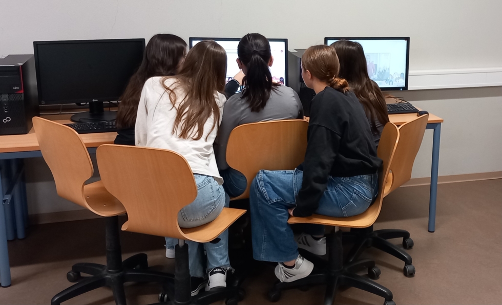 Girls'Day-Teilnehmerinnen mit Warnwesten von hinten fotografiert vor einem Computer