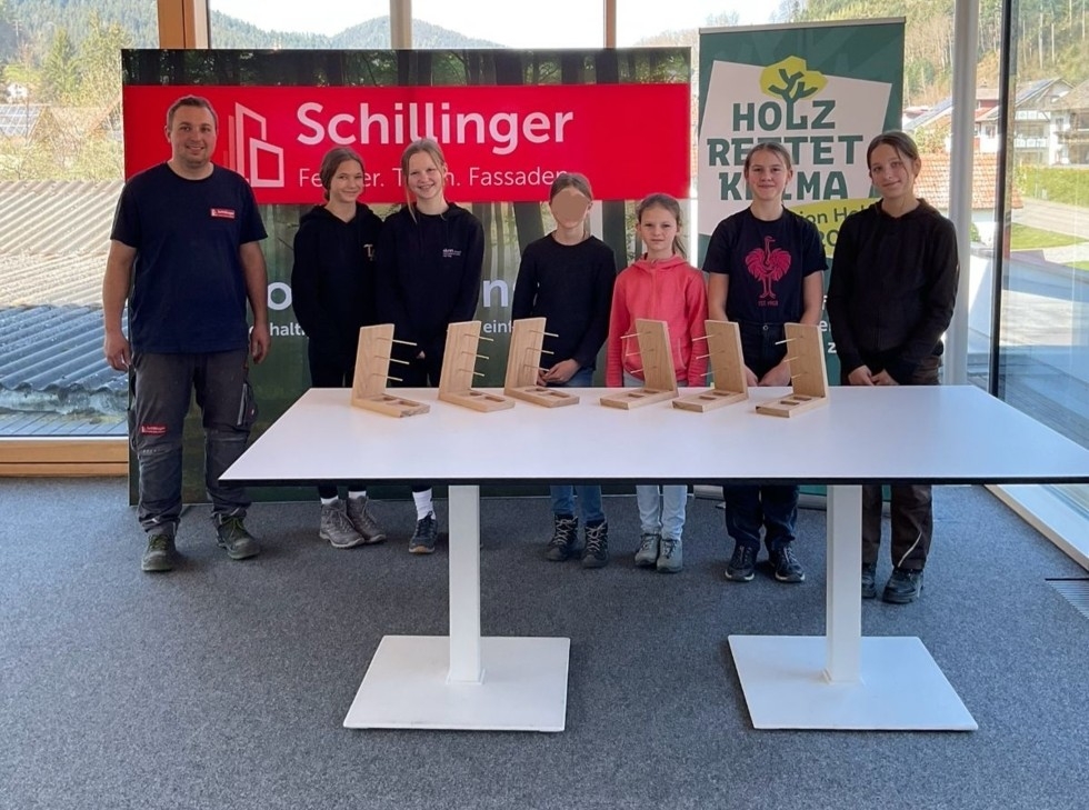 Girls'Day-Teilnehmerinnen mit Mitarbeiter vor Firmenlogo