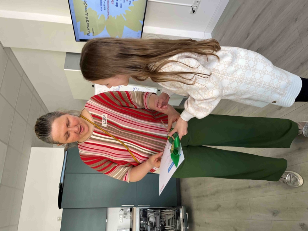 Girls' Day-Teilnehmerin erhält Teilnahmebescheinigung von einer Mitarbeiterin in einem modernen Raum