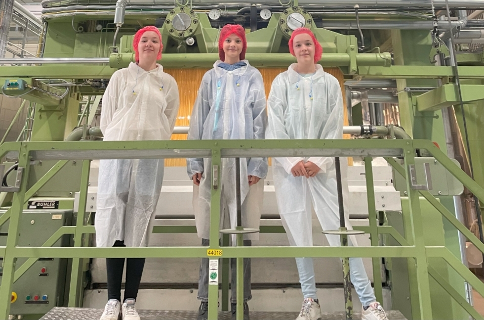 Girls'Day-Teilnehmerinnen mit Schutzanzügen vor Maschine